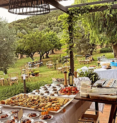 Catering allestito e preparato dal team da Alcide, in un giardino in Toscana vari tavoli con mono porzioni di piatti tipici del ristorante toscano proponendo un menù stagionale.