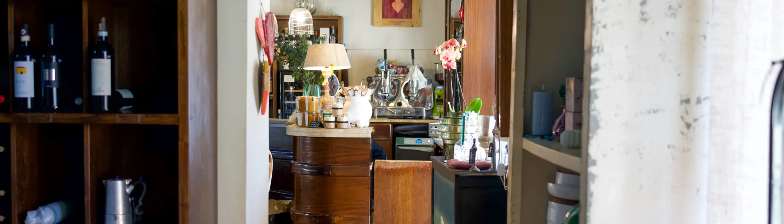 Interno ristornate con bancone in primo piano delle bottiglie di vino e degli elementi d'arredo per la tavola, nel ristorante da Alcide a Venturina in Toscana.