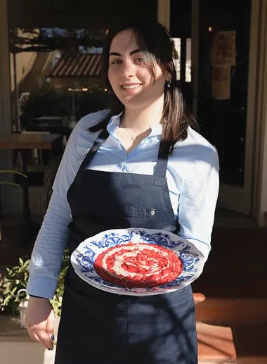 Margherita, cameriera della brigata del ristornate in Toscana, con in mano un piatto con risotto al melograno con gorgonzola, appena preparato nel ristorante da Alcide a Venturina, in Toscana. 