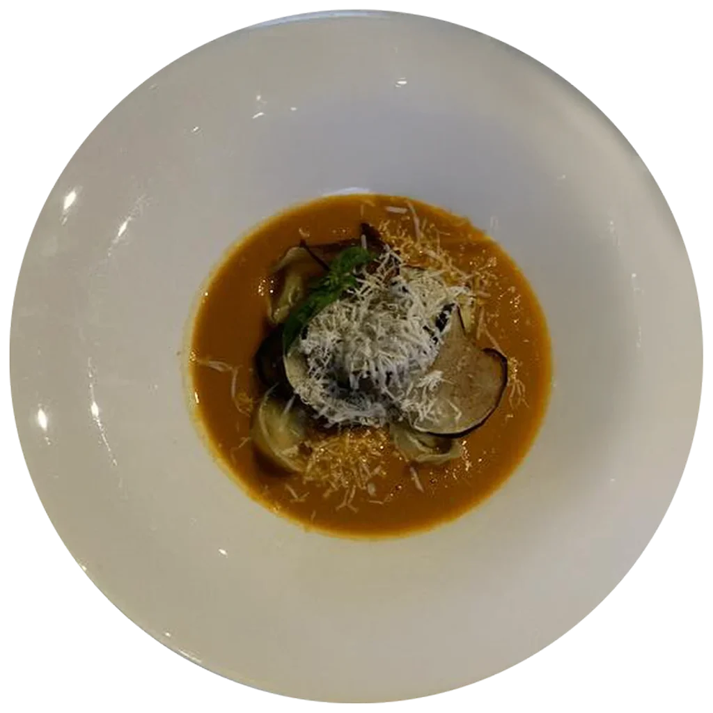 Tortelli di melanzane con crema di pomodori tre colori e scaglie di pecorino, piatto del ristorante Da Alcide a Venturina, in Toscana.